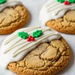 Christmas sugar cookies decorated with white icing and holly leaf designs on parchment paper.