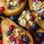Baked pears with fresh berries, honey, walnuts, and blue cheese served on a plate.